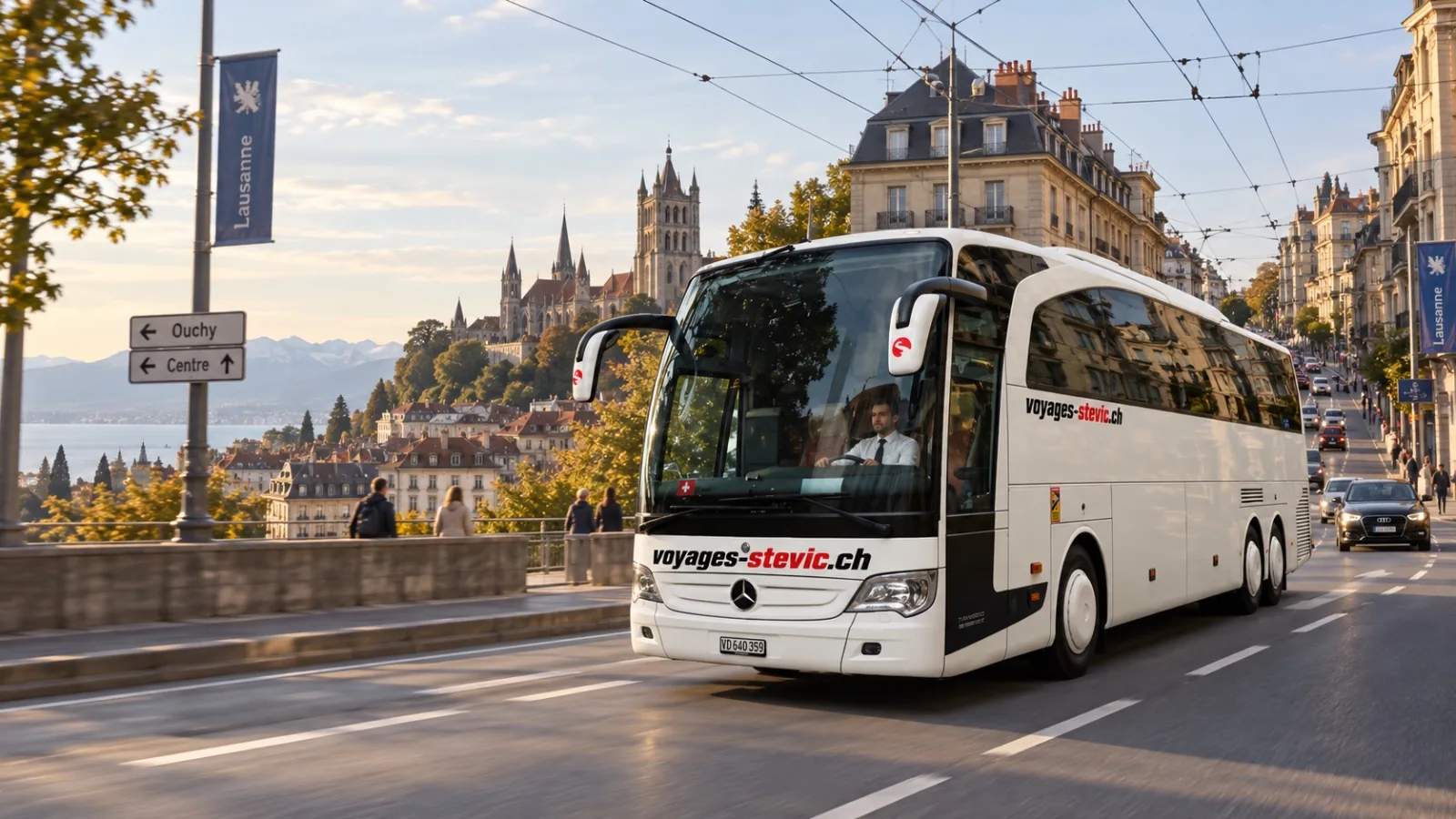 Autocar Mercedes-Benz Travego de Voyages Stevic Sàrl en circulation à Lausanne, la cathédrale en arrière-plan