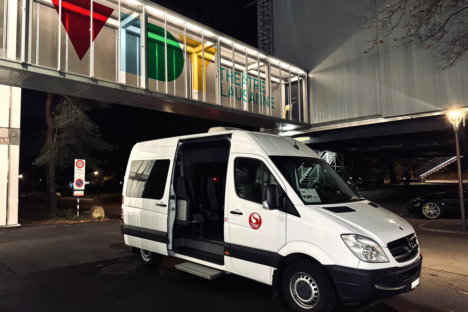 Minibus Sprinter 13 places de Voyages Stevic Sàrl en soirée devant le Théâtre de Vidy