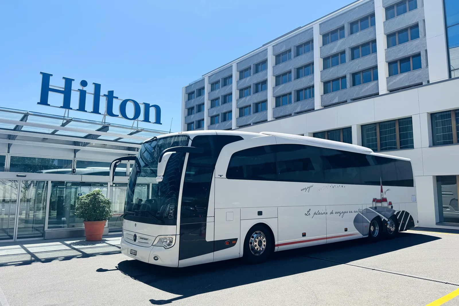 Autocar Mercedes-Benz Travego de Voyages Stevic Sàrl devant un hôtel Hilton